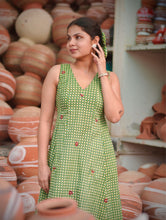 Woman wearing Meadow Bloom Olive Green Cotton Maxi Dress featuring gingham checks, floral motifs, V-neck design, and flowy A-line silhouette in breathable cotton fabric.