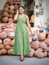 Woman wearing Meadow Bloom Olive Green Cotton Maxi Dress featuring gingham checks, floral motifs, V-neck design, and flowy A-line silhouette in breathable cotton fabric.