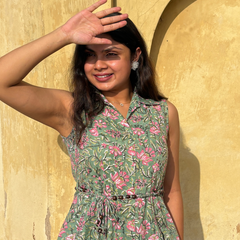 Woman wearing a mint green floral sleeveless A-line dress with a collar neck, adjustable waist tie-up, and knee-length silhouette in an outdoor setting.