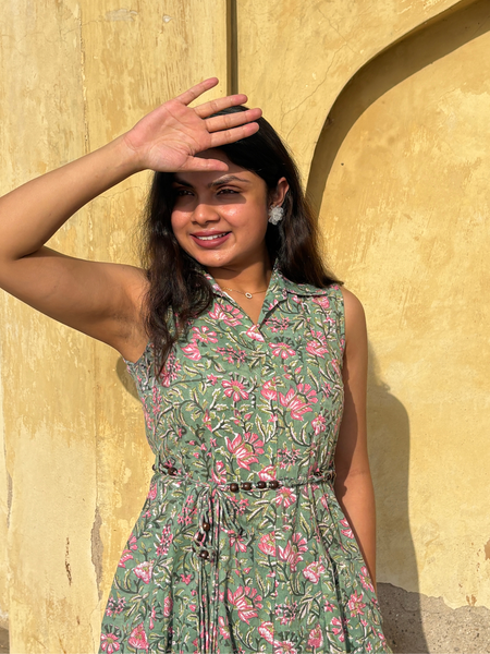 Woman wearing a mint green floral sleeveless A-line dress with a collar neck, adjustable waist tie-up, and knee-length silhouette in an outdoor setting.